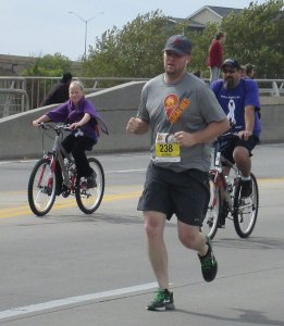 Justin running the Prairie Fire Marathon with his support crew surrounding him.