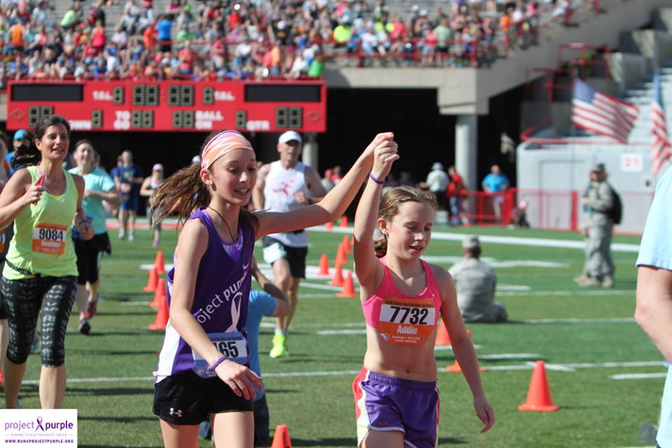 Project Purple runner, Addison Earnest, crosses the finish line with her friend.